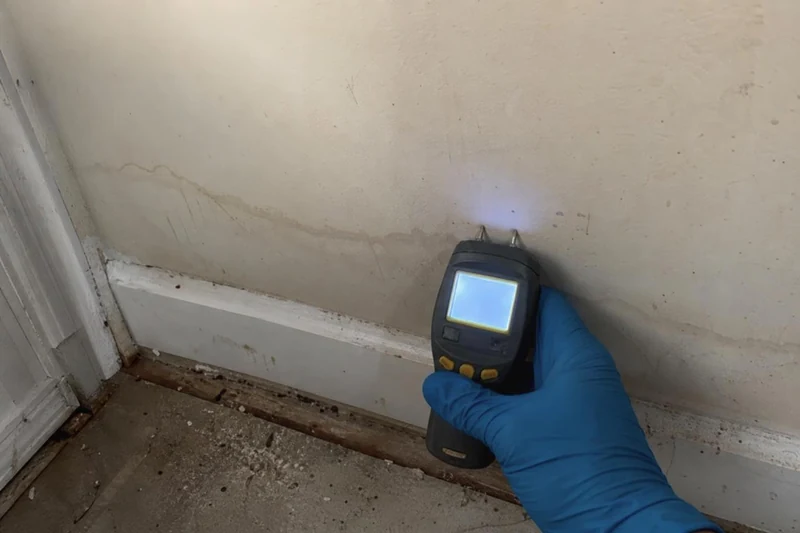 A moisture meter reading the water line on a wall during an emergency call in McKinney