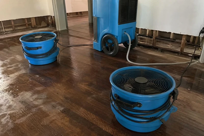 Two air movers and a dehumidifier pulling moisture out of hardwood flooring in a Stewart Peninsula home near Lewisville Lake